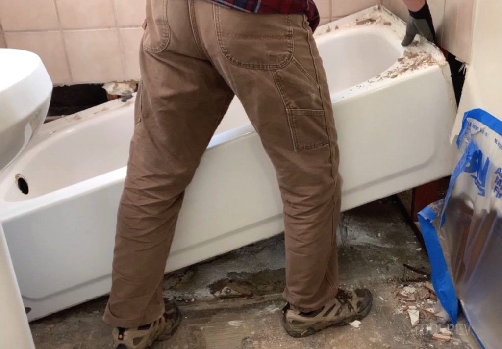 Worker lifting bathtub up from floor.