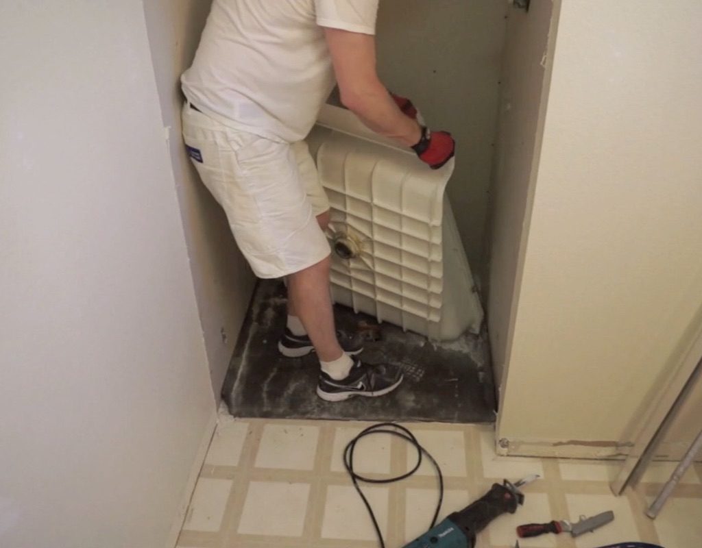 worker lifting shower pan out of shower stall