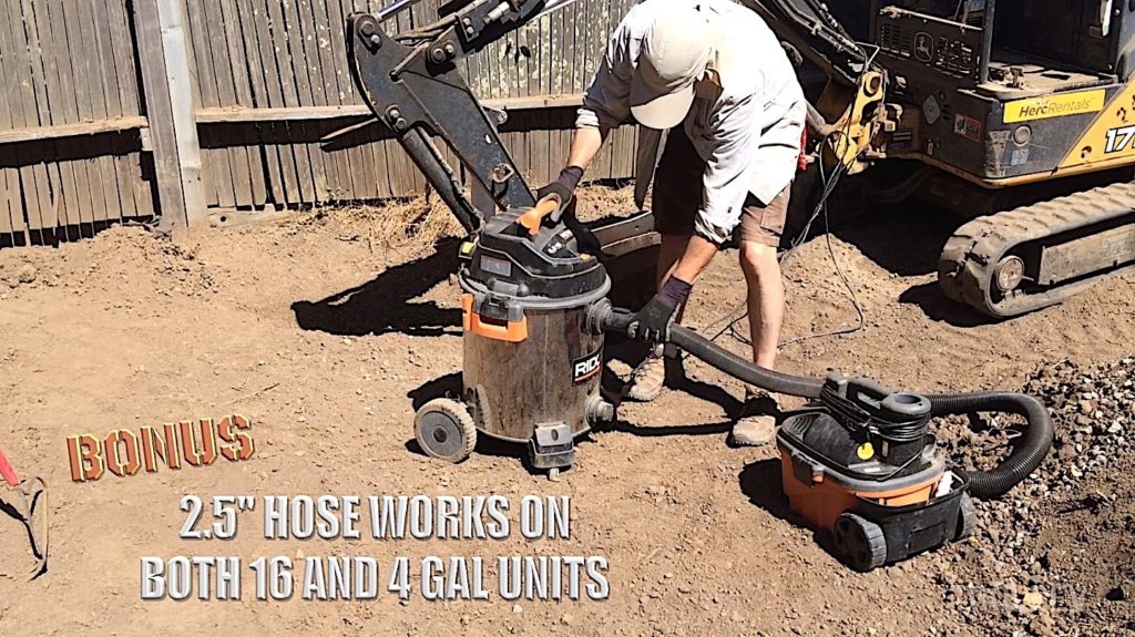 Man changing hose between large and small shop vac outdoors.