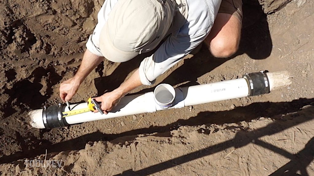 Worker measuring and marking PVC pipe with marker.