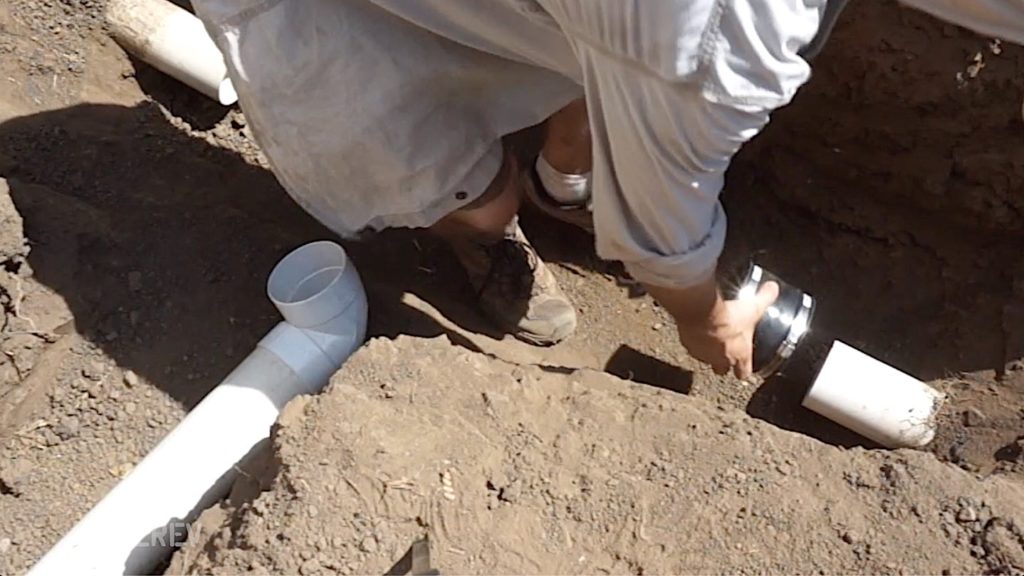 Man placing couplings over cut drain line.