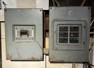 two residential electrical panel boxes on a garage wall.