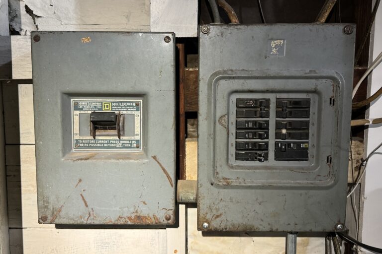 two residential electrical panel boxes on a garage wall.