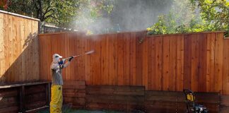 Man pressure washing a fence.
