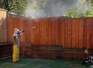 Man pressure washing a fence.
