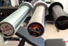 three short barbells from REP and Rogue fitness on a rack.