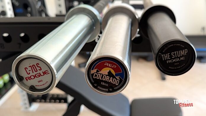 three short barbells from REP and Rogue fitness on a rack.