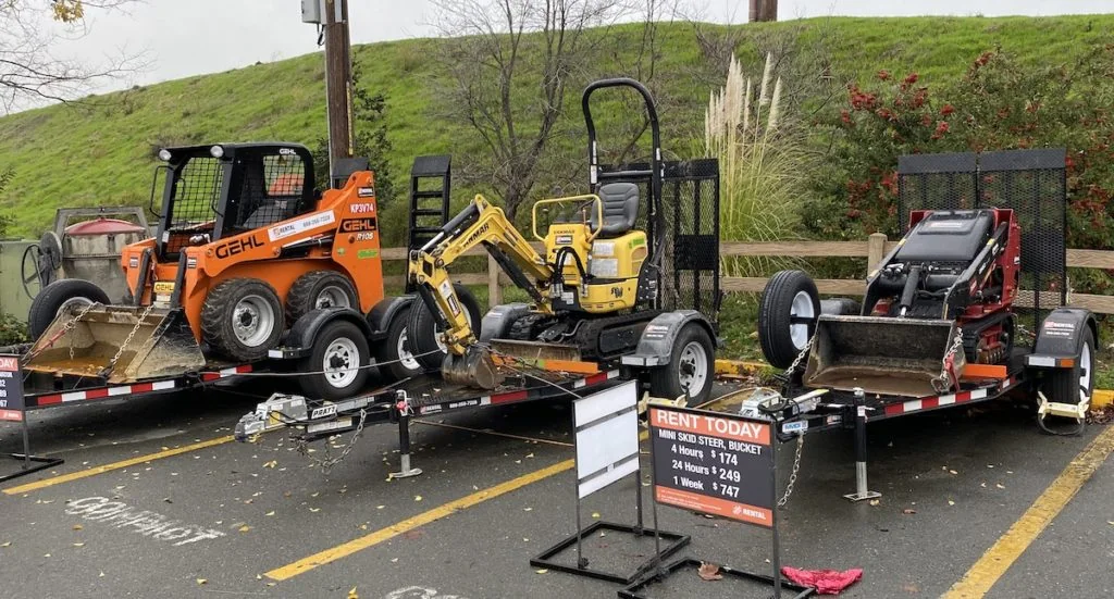 Rental trailers loaded with a Gehl skid steer, mini excavator, and mini skid steer