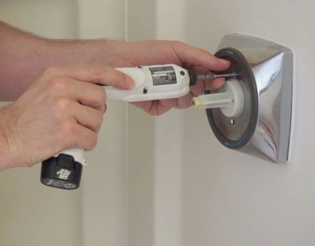Worker using a drill to remove shower fixtures safely