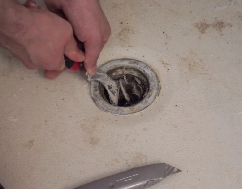 Removing caulking and grate from shower drain