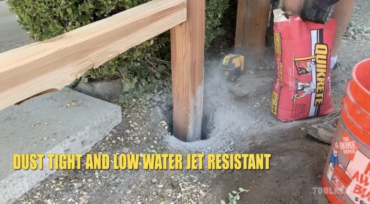 DeWalt laser level with dust on it next to fence post.