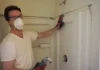 How to Remove a Shower: Easy Step by Step Guide Worker in a dust mask removing a shower surround wall
