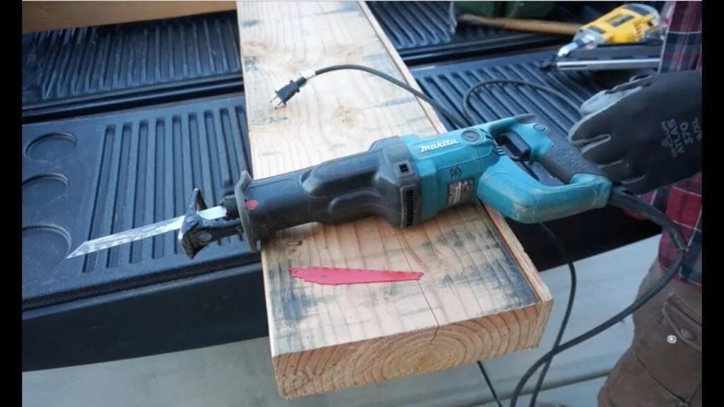 Makita corded reciprocating saw resting on a board in a truck bed Makita corded reciprocating saw resting on a board in a truck bed